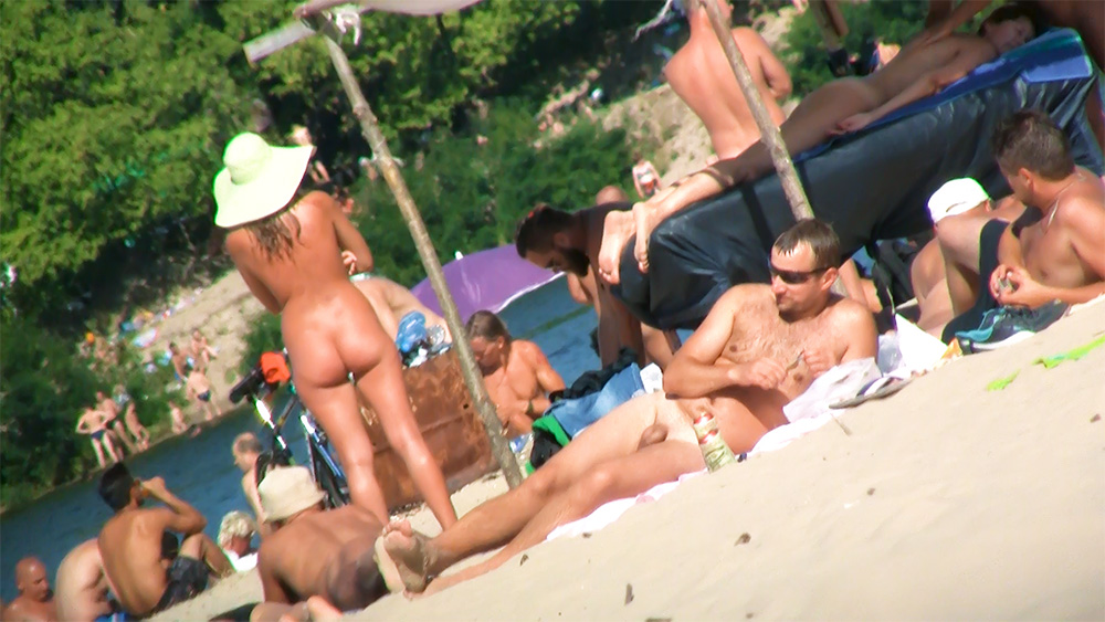 Bílý klobouk se širokou krempou na rušném pobřeží nudistické pláže