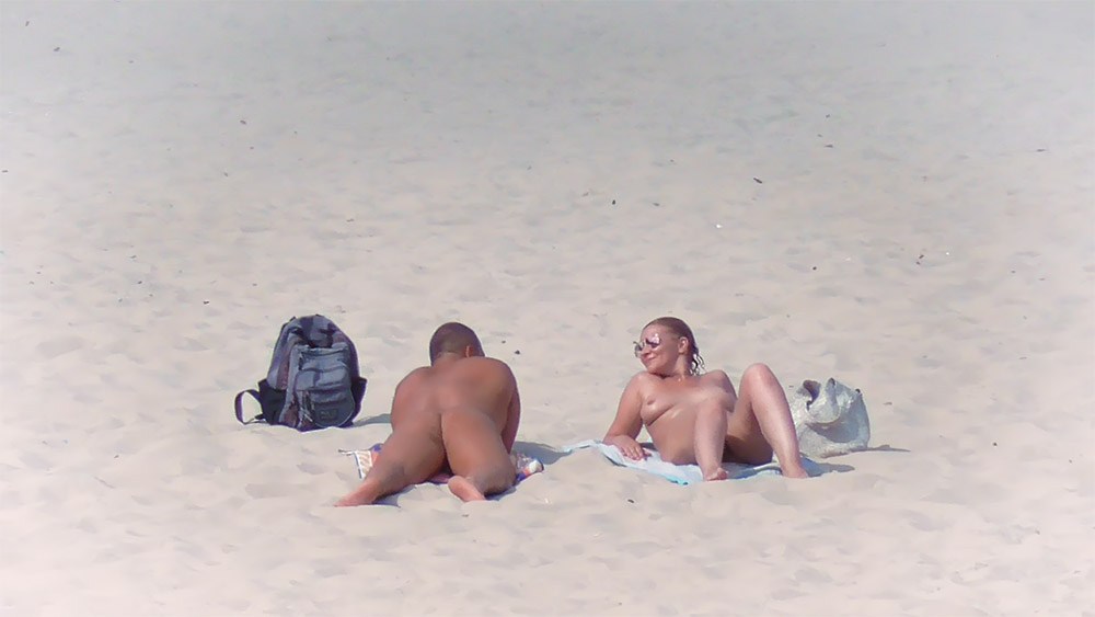 Two Nudists on a Sandy Beach with Sunglasses
