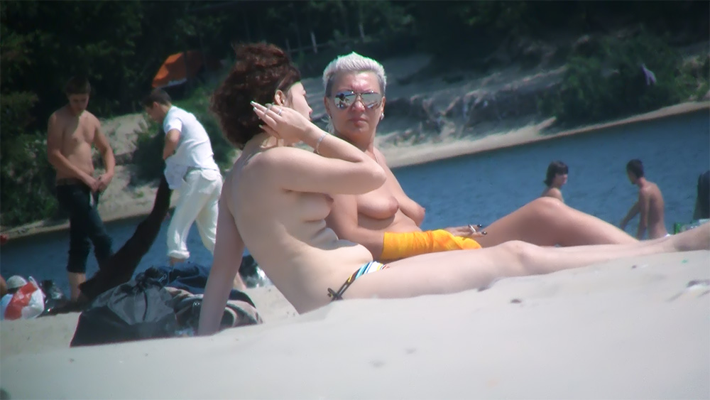 Dwie kobiety topless na plaży w kolorowych dołach od bikini