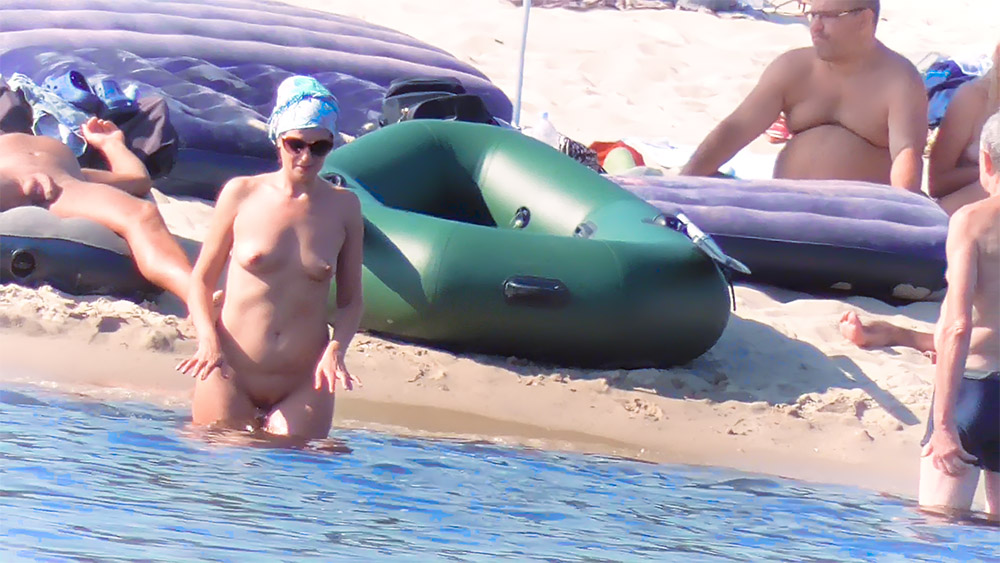One Nudist in a Blue Head Wrap by an Inflatable Raft