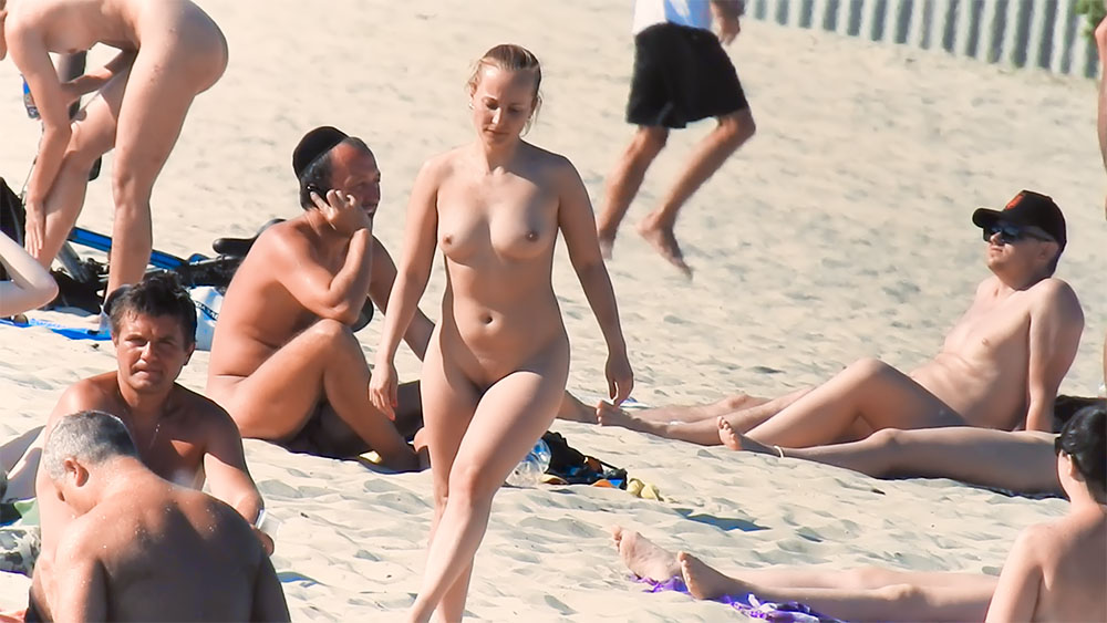 Quatro nudistas reunidos na areia junto à orla