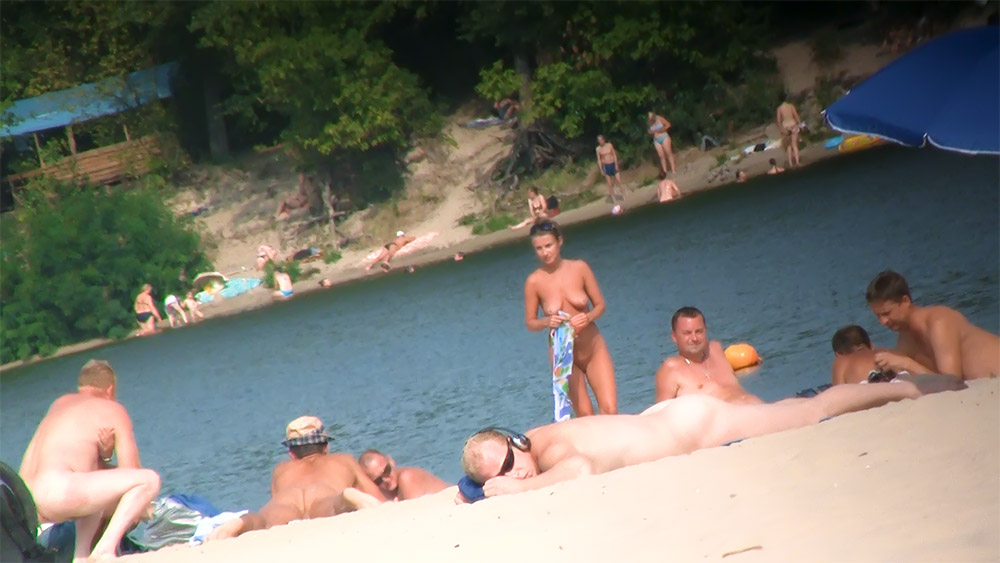 Vier naturisten ontspannen aan een rustige rivieroever