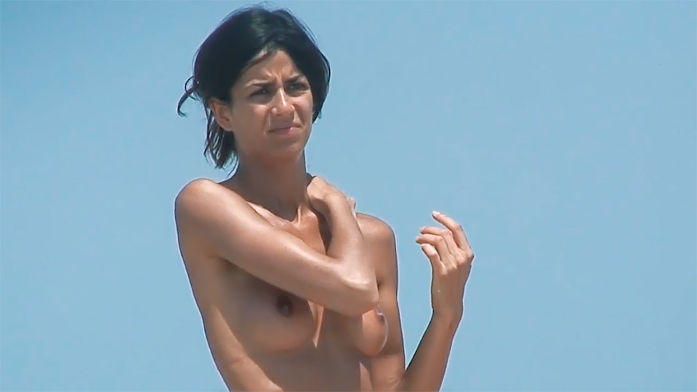 Bright Sky Topless Beach Scene with Sunscreen Bottle