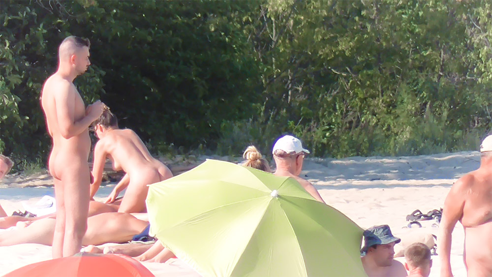 Two Nudists Gathering Under a Bright Yellow Umbrella