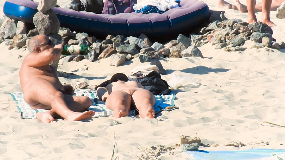 Modrý vzorovaný ručník na písku na nudistické pláži