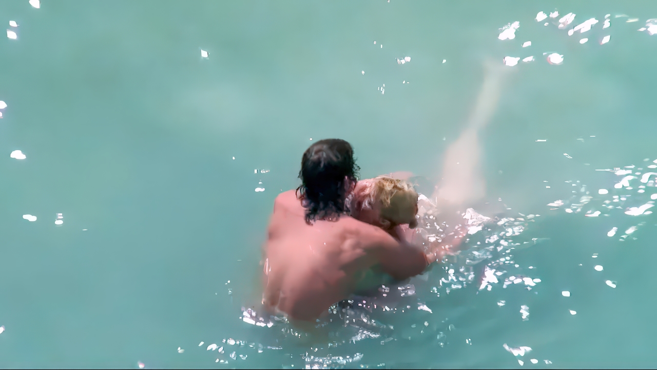 Nudists embracing in bright turquoise water with rising splashes