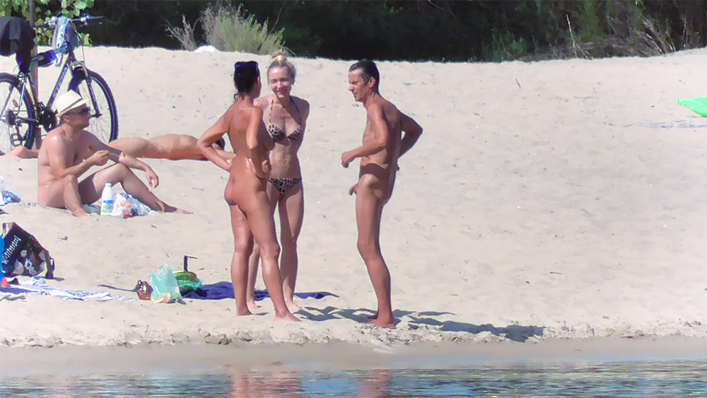 Three Naturists Talking Near the Water's Edge
