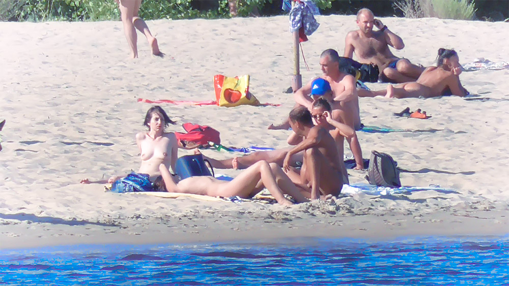 Naturisté sedí a povídají si na písčité pláži