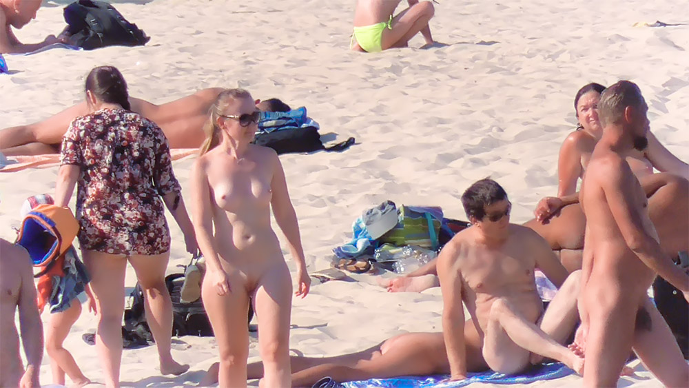 Completamente Nua Junto a Sacos numa Praia de Nudismo